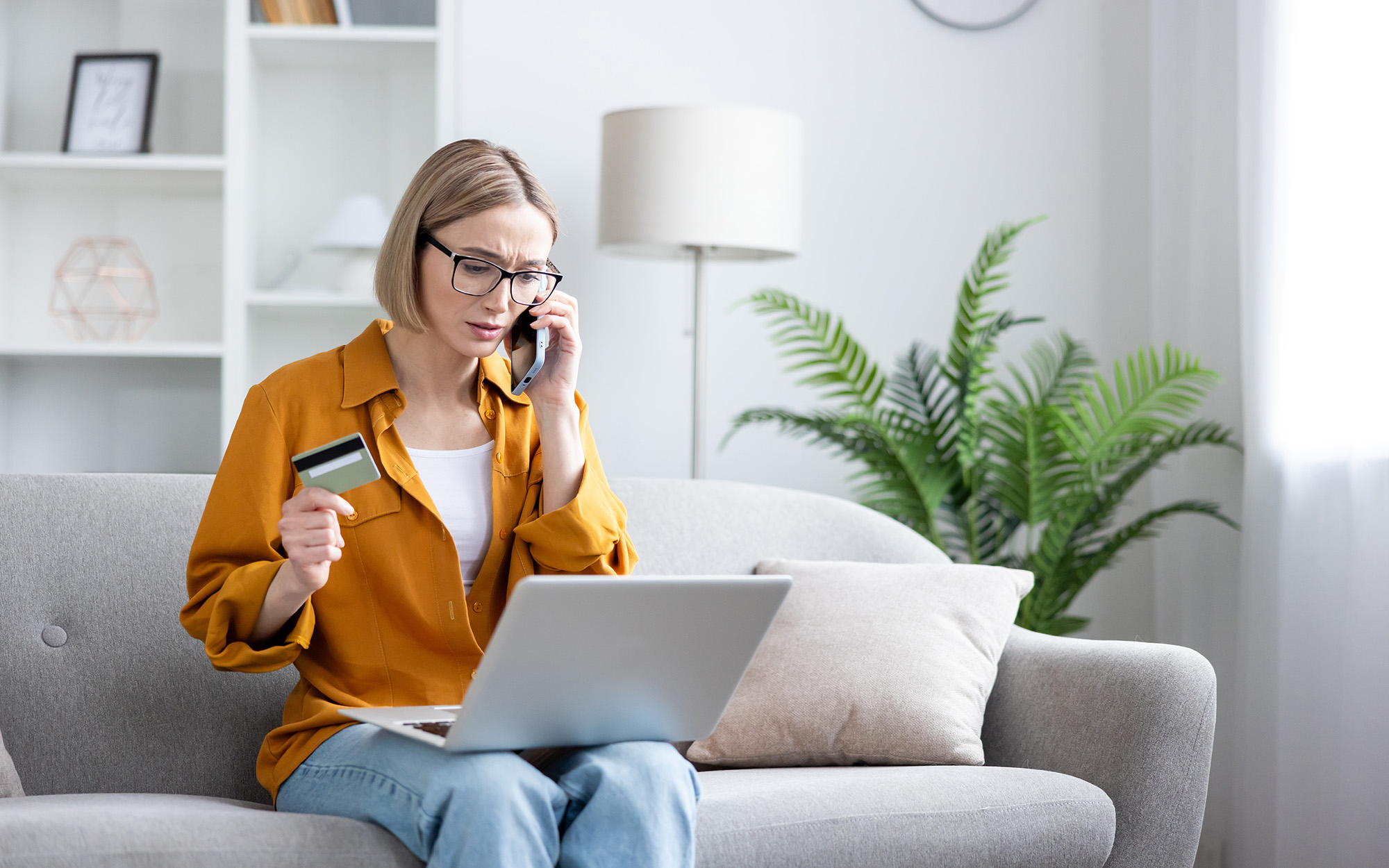 person on laptop while holding credit card and phone